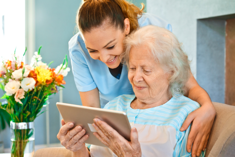 Nurse looking at senior woman using digital tablet Nurse looking at senior woman using digital tablet